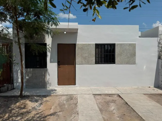 La misma fachada después: pintada, con puerta de madera nueva y ventanas con herrería.